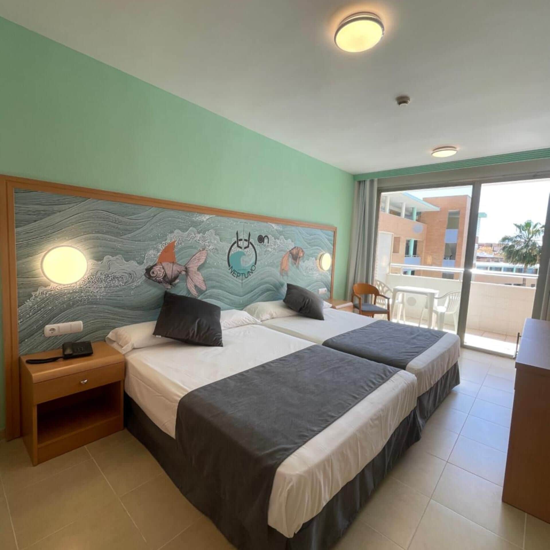A hotel room with two beds, a nightstand, a telephone, and a view of the outside.