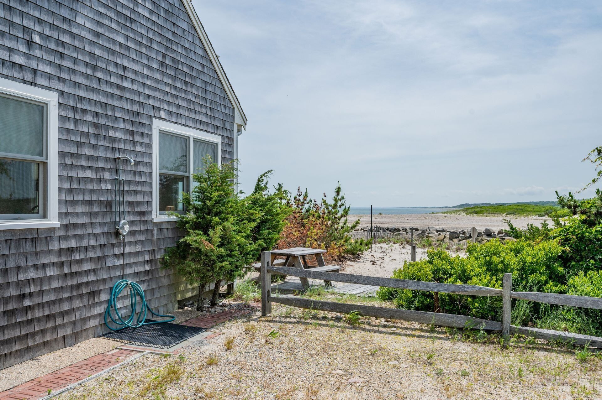 Ein Haus mit Blick auf den Strand und einem Holzzaun im Vordergrund.