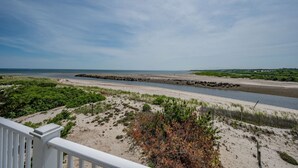 Vista costera con playa arenosa, rompeolas rocoso y cielo despejado.