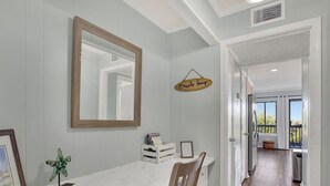 A dining area with a marble countertop, a wooden chair, a hanging sign, and a view to a balcony. - Beautiful Water Views, Steps to Beach (Tybee Island)
