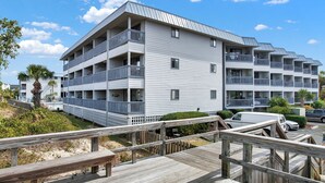 A multi-story hotel with balconies, a wooden deck, and a pool area. - Beautiful Water Views, Steps to Beach (Tybee Island)