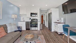 A compact living space with a kitchenette, a dining area, and a seating area with a sofa and a coffee table. - Beautiful Water Views, Steps to Beach (Tybee Island)