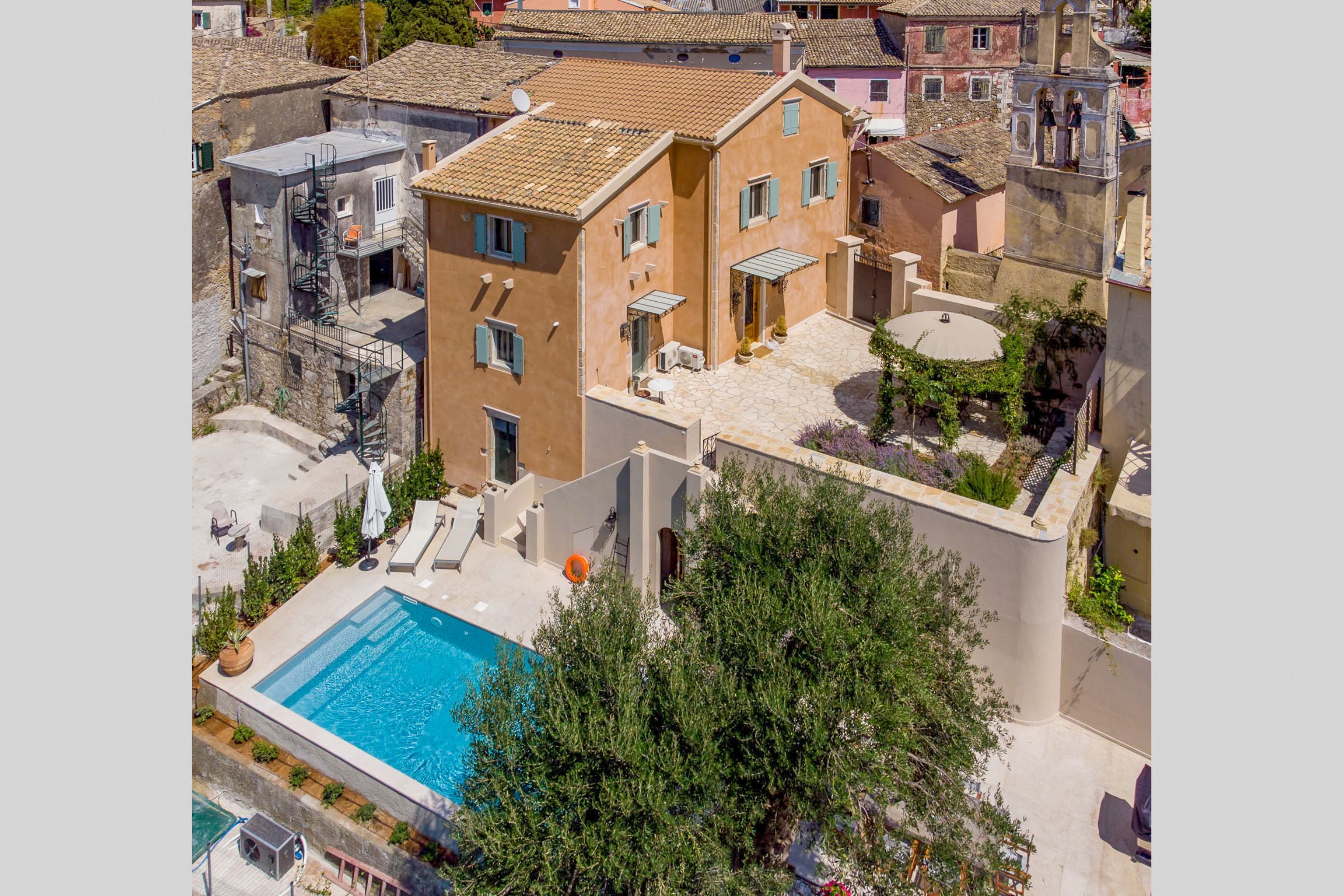 Ein Wohngebäude mit Schwimmbad, Außenbereich mit Sitzgelegenheiten und einer Treppe zu einer Dachterrasse.