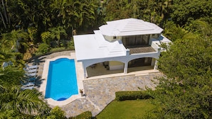 A modern house with a swimming pool, surrounded by lush greenery. - Quaint Villa with Beautiful gardens (Playa Encuentro)