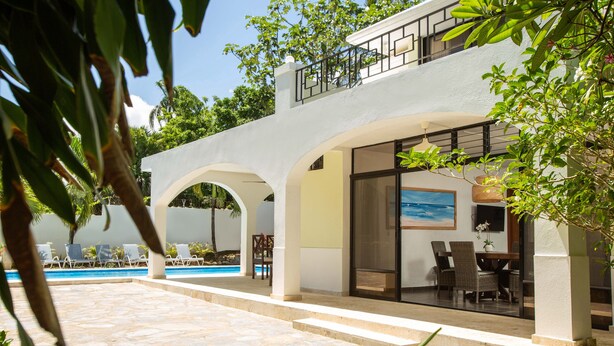 A modern building with a pool, outdoor seating, and a balcony. - Quaint Villa with Beautiful gardens (Playa Encuentro)