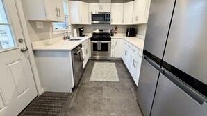 A modern kitchen with white cabinets, stainless steel appliances, and a tiled floor. - Incredible 5 bed 2 bath w/ HOT TUB close to Pitt (Bethel Park)