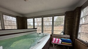 A hot tub in a room with large windows, a bench, and a table with towels. - Incredible 5 bed 2 bath w/ HOT TUB close to Pitt (Bethel Park)