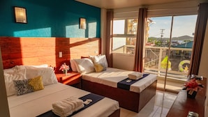 Habitación de hotel con dos camas, cabecera de madera, un ventanal con vistas y una pequeña mesa con un florero.