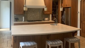A spacious kitchen with a large island, wooden cabinets, and modern appliances.