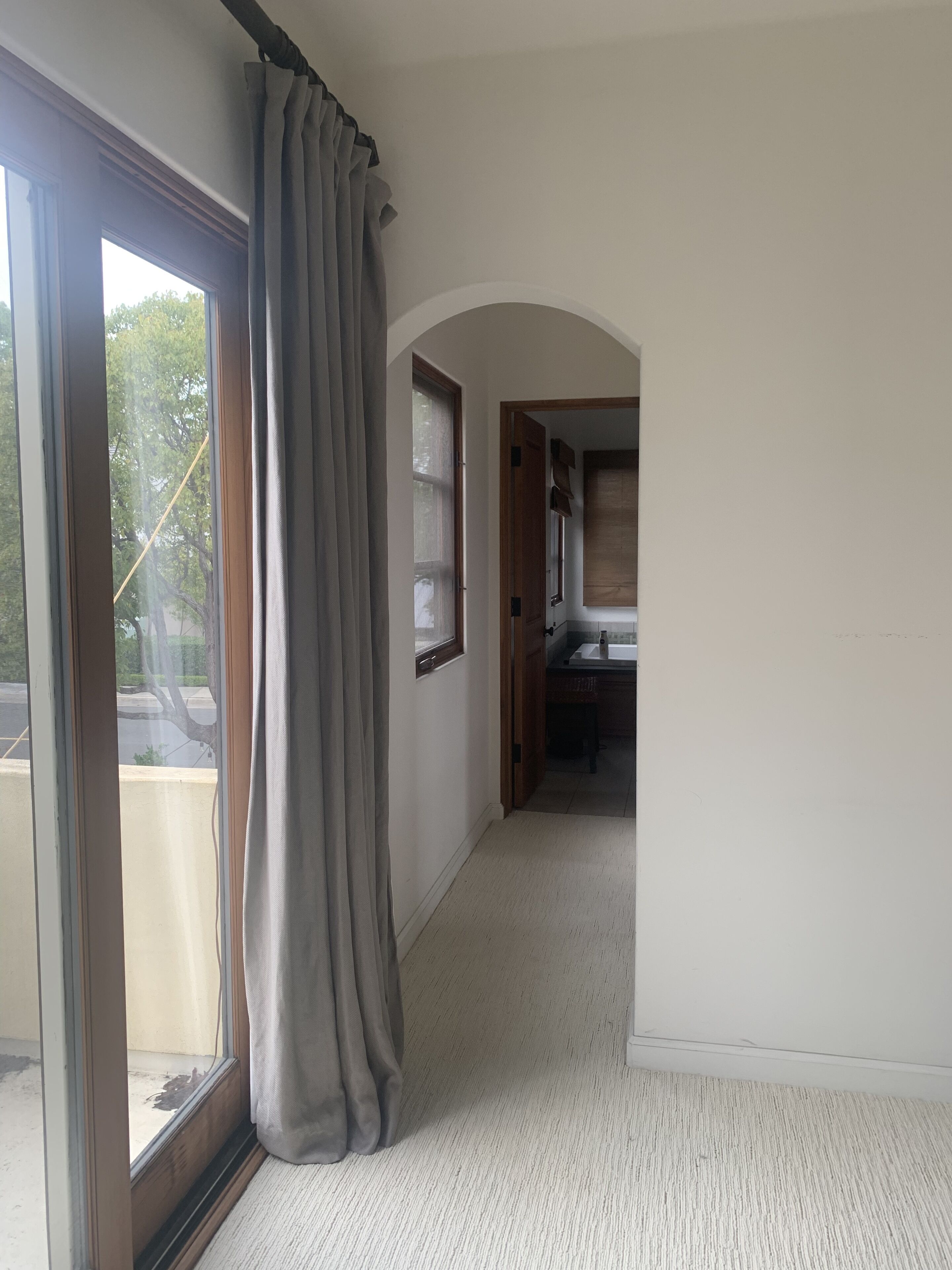 A hallway with a sliding glass door, a wooden door leading to a kitchen, and a carpeted floor.