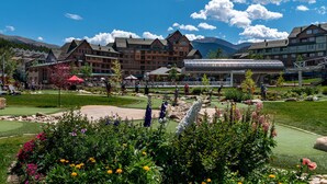 Un hotel con varias edificaciones, un campo de golf y montañas al fondo.
