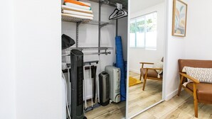 Una camera compatta con un armadio a specchio, un divano in pelle marrone e una sedia in legno.