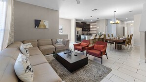 A modern living room with a sectional sofa, a coffee table, and a dining area with chairs and a table.