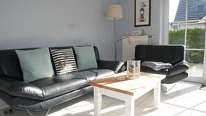 A modern living room with a black leather sofa, a wooden coffee table, and a floor lamp.