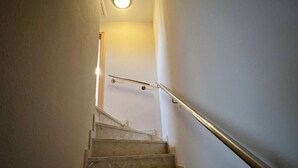 A staircase with a handrail, leading to a room with a door at the top.
