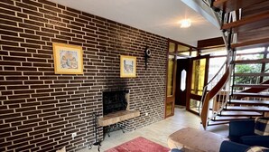 Una sala de estar con chimenea de ladrillo, una escalera y una alfombra roja.