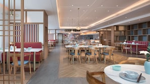 Un restaurante espacioso con varias zonas de comedor, mobiliario de madera y un diseño de techo moderno.
