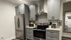 A modern kitchen with grey cabinets, stainless steel appliances, and a wooden floor.