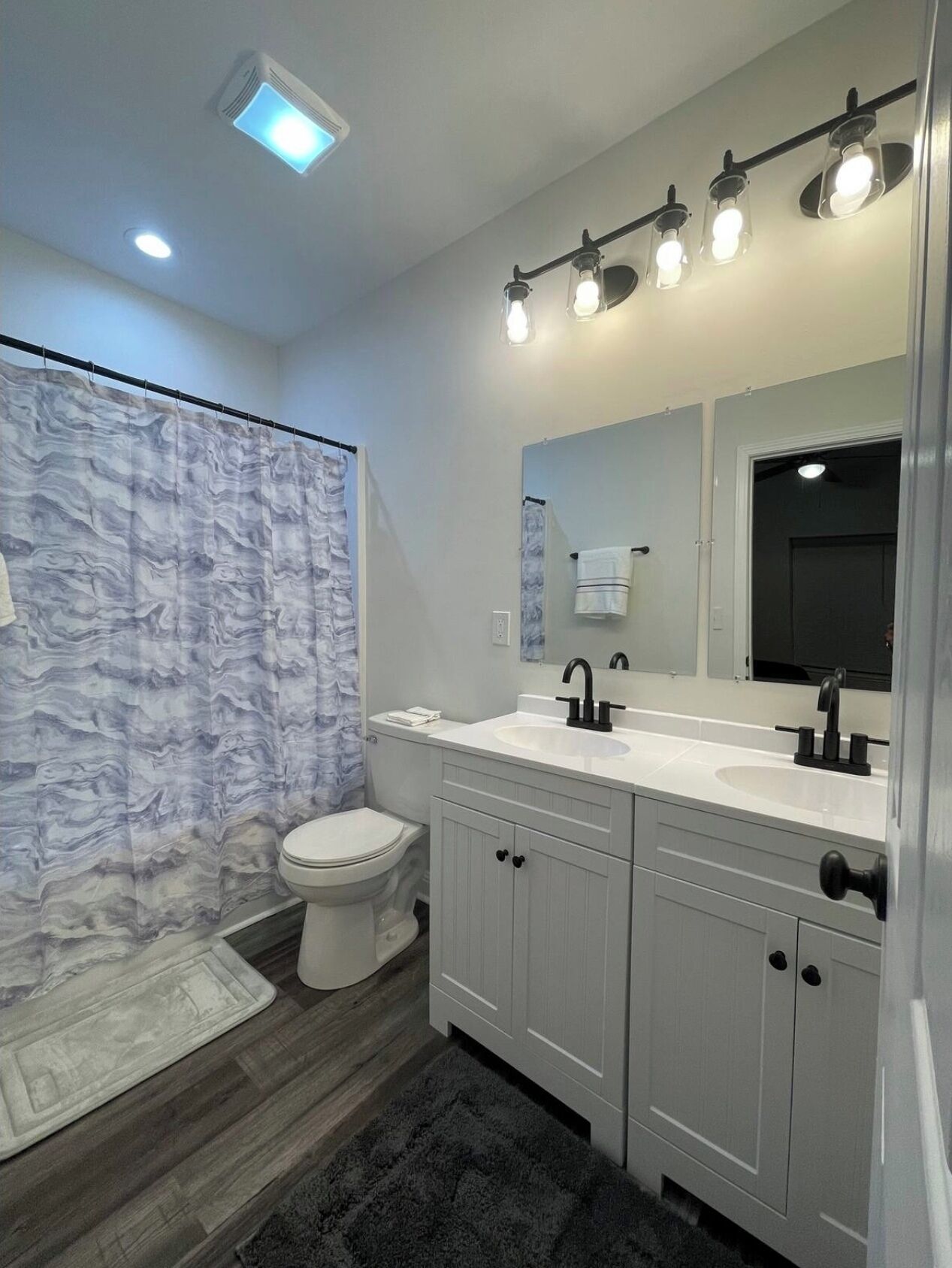 A modern bathroom with a shower curtain, toilet, sink, and vanity.