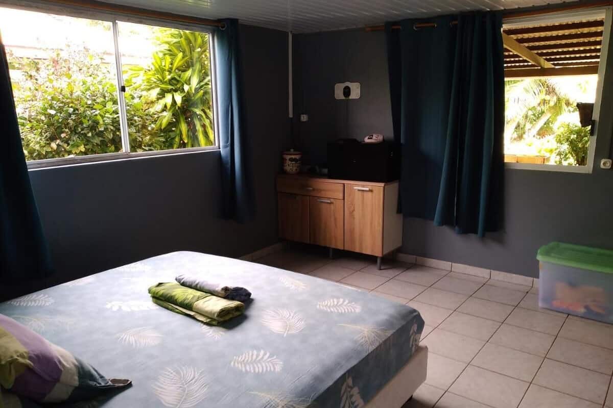 A bedroom with a bed, a wooden cabinet, and a window with curtains.