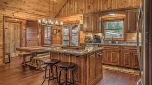 Una cucina in stile rustico con elementi in legno, un'isola spaziosa con sgabelli e una parete a mosaico in pietra.