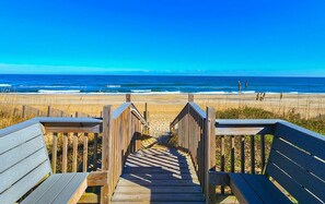 Ein Holzsteg führt zu einem Strand mit freiem Blick auf den Ozean.