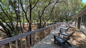 Eine Holzterrasse mit Geländer, Bänken und einem Gebäude mit großen Fenstern im Hintergrund.