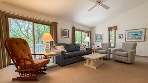 Ein Wohnzimmer mit Sofa, Sesseln, einem Schaukelstuhl, einem Couchtisch und einem Deckenventilator.
