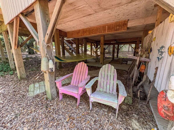 Une structure rustique en bois, avec deux fauteuils Adirondack placés sous un porche abrité.