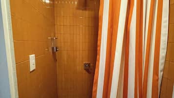Un bany petit amb rajoles, un vàter i una porta amb mànega.