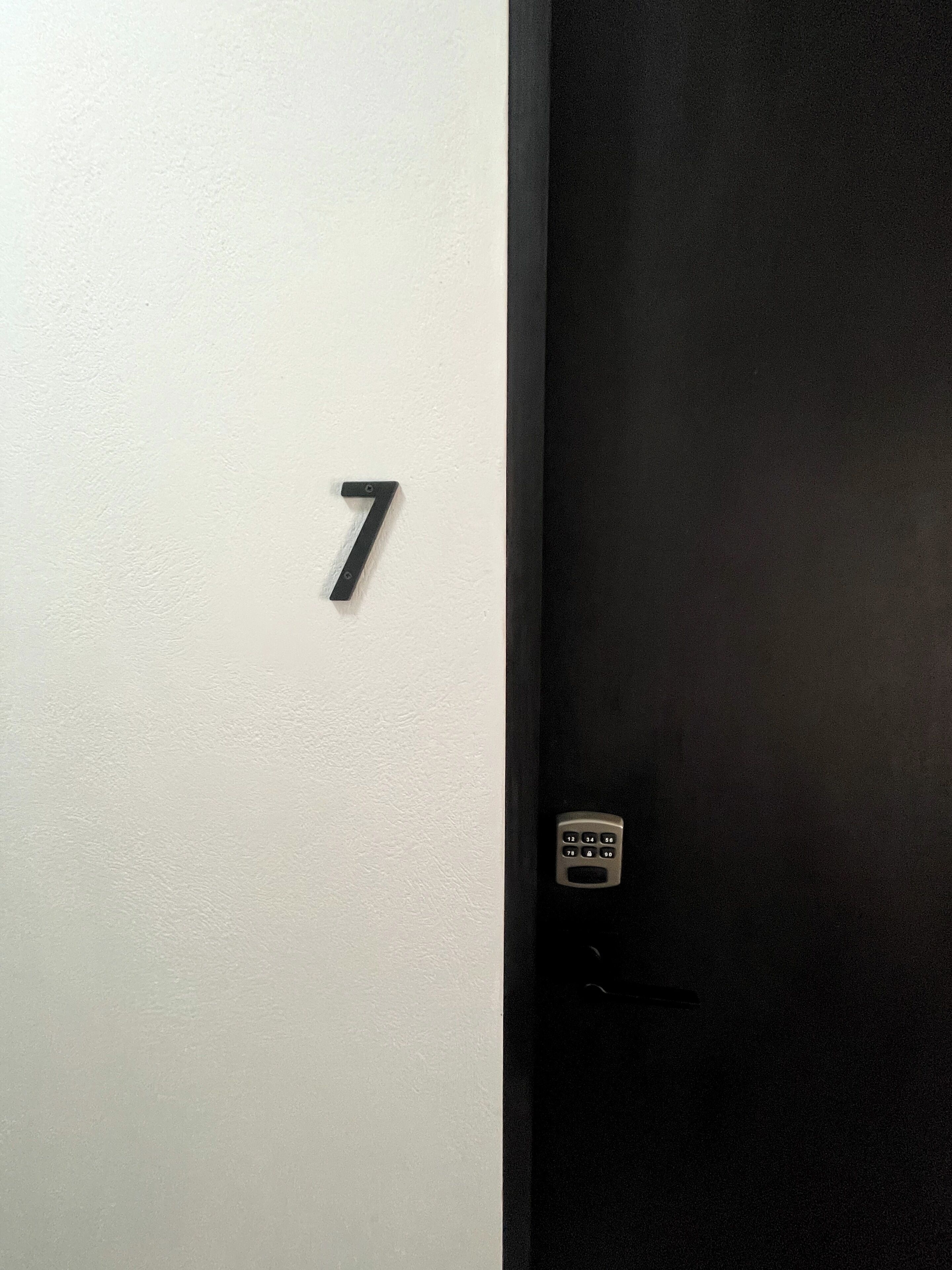 A door with a number 7 sign on the wall and a keypad lock.