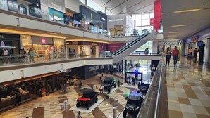 Un centre commercial à plusieurs niveaux, comprenant divers magasins, dont une boutique d’usine Michael Kors, et un espace central ouvert où sont exposés des quads.