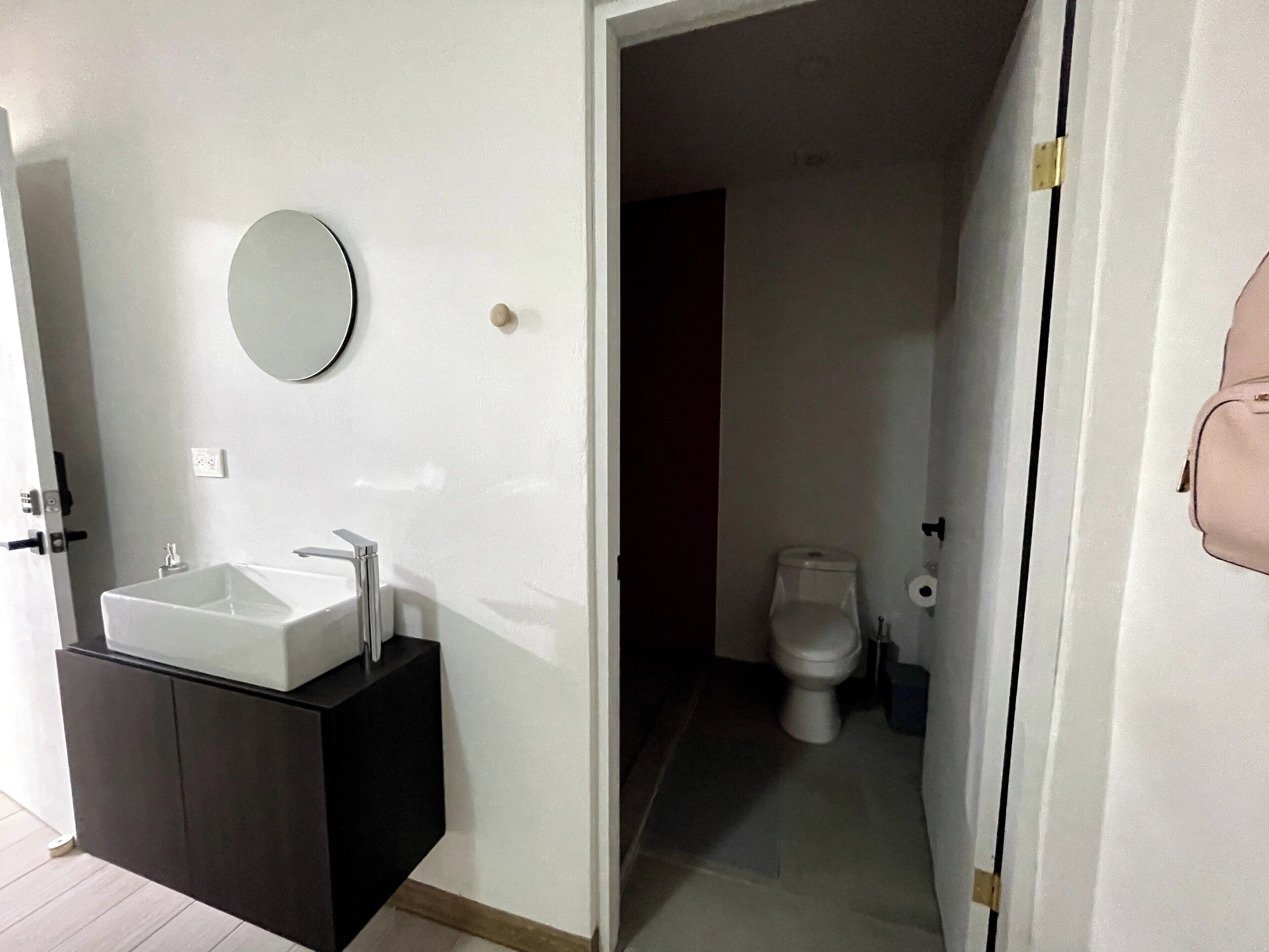 Un baño con lavamanos blanco, espejo y retrete.
