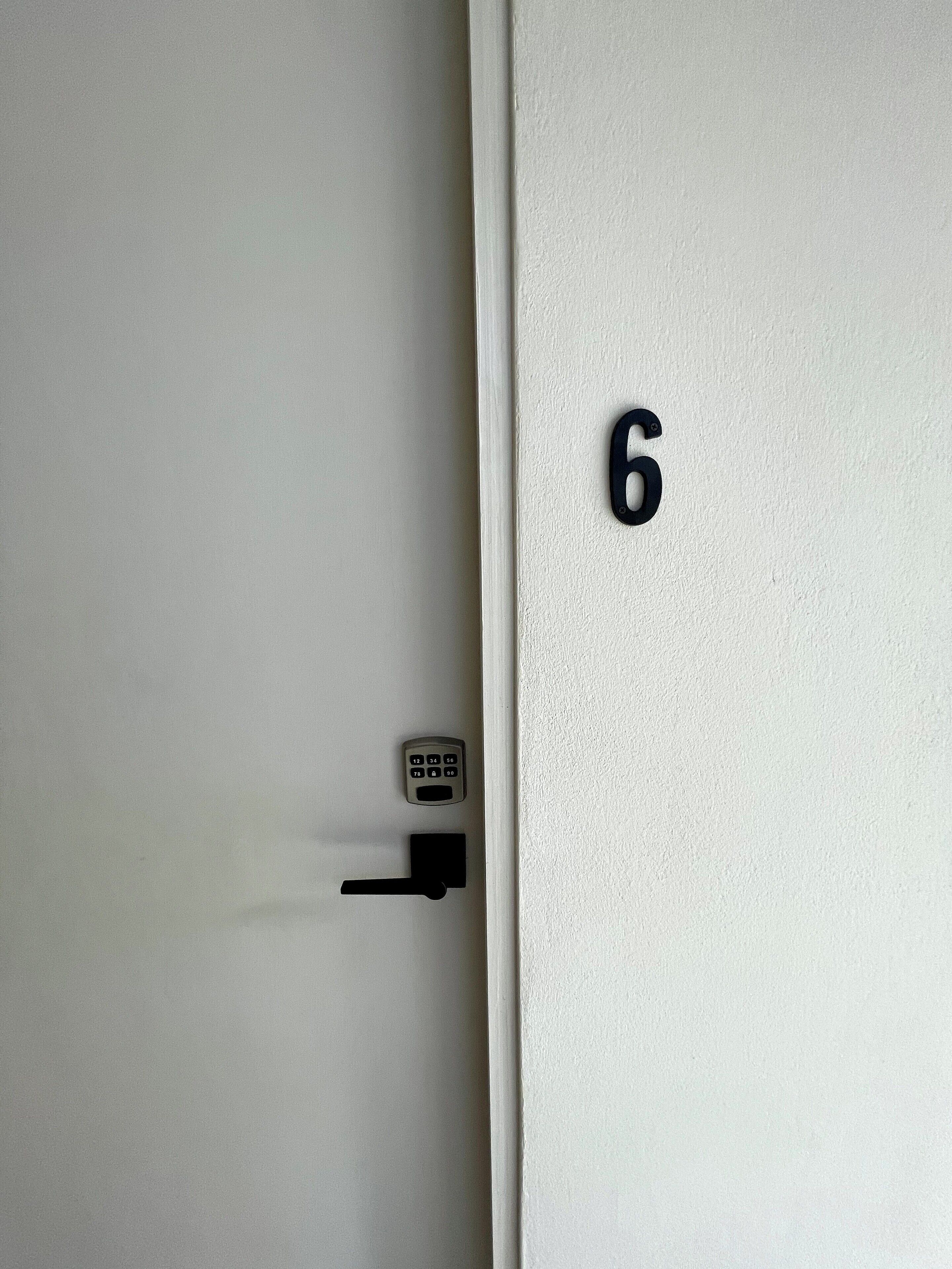 A door with a numeric keypad lock and the number 6 on the door.