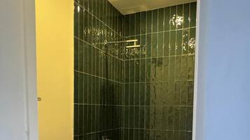 A small, enclosed bathroom with a toilet and a shower stall.