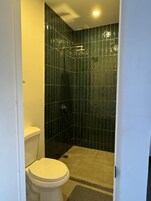 Un baño pequeño y cerrado con inodoro y cabina de ducha.