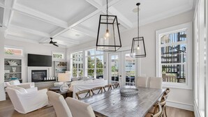 A spacious living room with a large wooden dining table, white sofas, and a fireplace.
