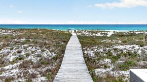 A wooden boardwalk leading to a beach with clear blue water.