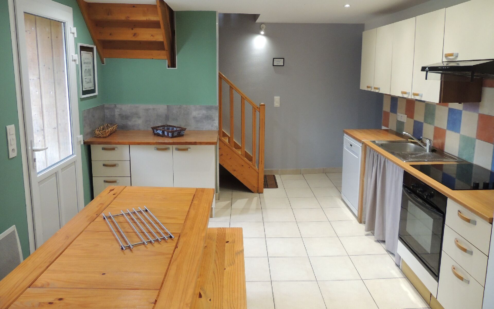 A compact kitchen with a wooden table, a small sink, and a dishwasher.