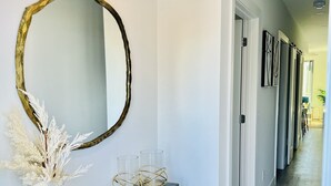 A hallway with a console table, a large mirror, and a vase with dried plants.