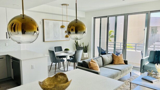 A modern living room with a dining area, large windows, and a balcony.