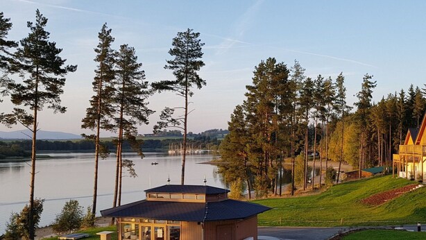 A lakeside lodge with outdoor seating and a small building with large windows. - Beautiful apartment for 2 guests with WIFI, TV, terrace and pets allowed (Lojzova Paseka)