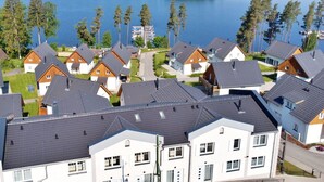 A residential area with houses near a lake, featuring a mix of modern and traditional architecture, surrounded by greenery and a clear view of the water. - Beautiful apartment for 2 guests with WIFI, TV, terrace and pets allowed (Lojzova Paseka)