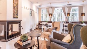 A modern living room with a fireplace, comfortable seating, and large windows offering a view of trees. - Beautiful apartment for 2 guests with WIFI, TV, terrace and pets allowed (Lojzova Paseka)