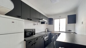 Een moderne keuken met zwart-wit keukenkastjes, een inbouwoven en een groot raam dat voor natuurlijk licht zorgt.