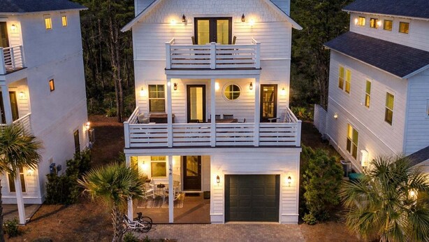 A two-story house with a balcony, a garage, and a driveway.