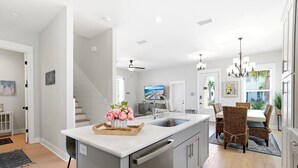 A modern kitchen with a central island, stainless steel appliances, and a dining area with wicker chairs.