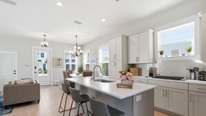 A modern kitchen with a central island, bar stools, and a large window.