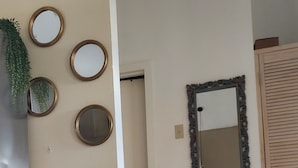 A modern living room with a sofa, a potted plant, and wall-mounted mirrors. - SUPREME LIVING VACATION HOME. Your home away from home!  (Portmore)