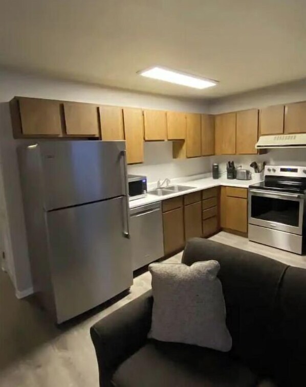 Compact kitchen with modern appliances, a couch, and neutral decor.